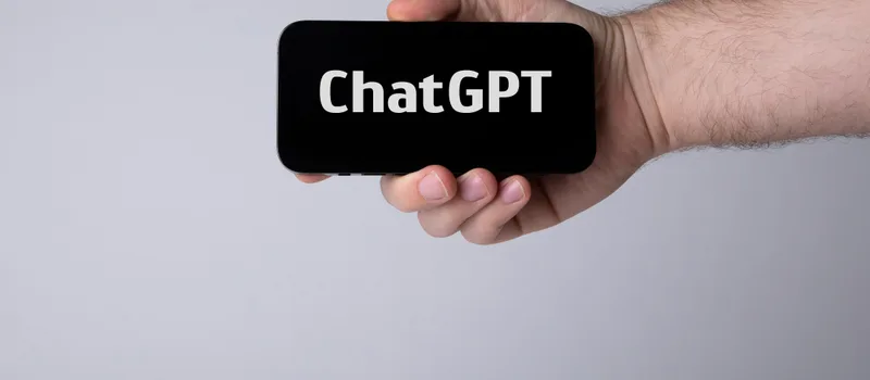 Hand holding a smartphone with ChatGPT – testing your own AI visibility